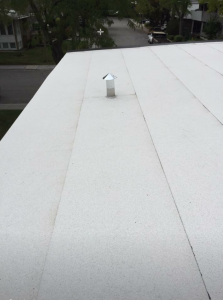 Un toit en membrane élastomère gris clair avec un conduit de cheminée