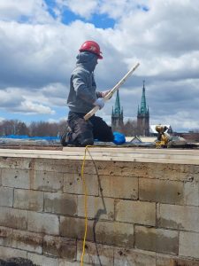 Un mur de briques réparé sur un toit après des travaux de toiture et de maçonnerie.